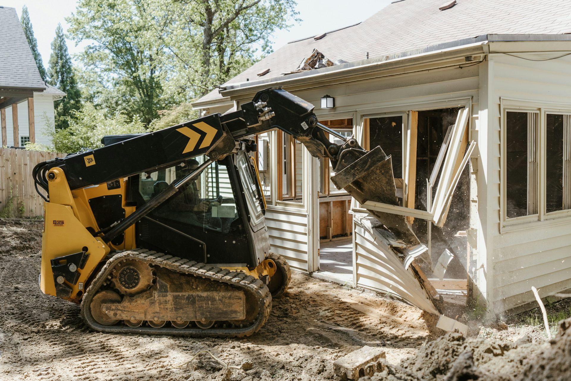 ein Bulldozer, der vor einem Haus Erde aushebt
