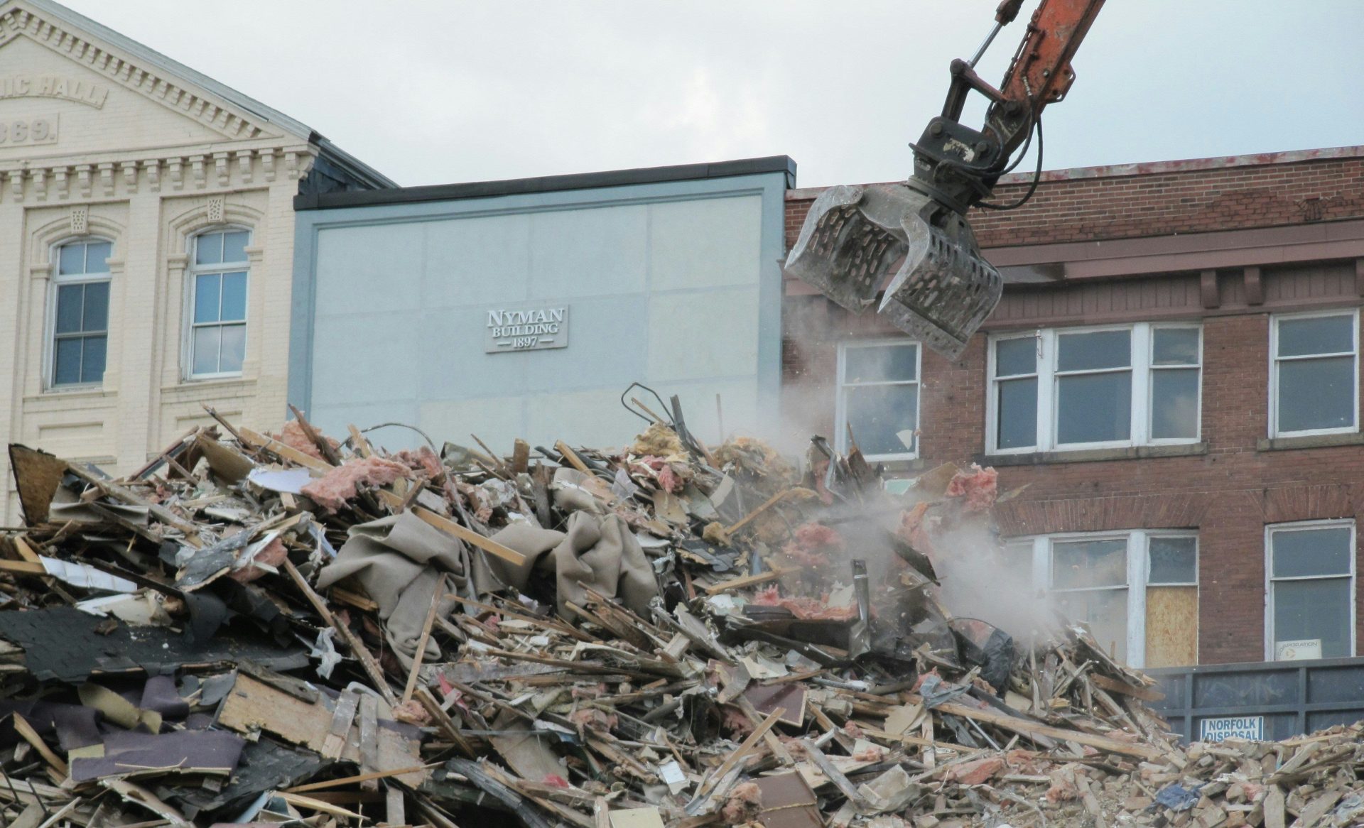 ein Bulldozer, der sich vor einem Gebäude durch einen Schuttberg gräbt